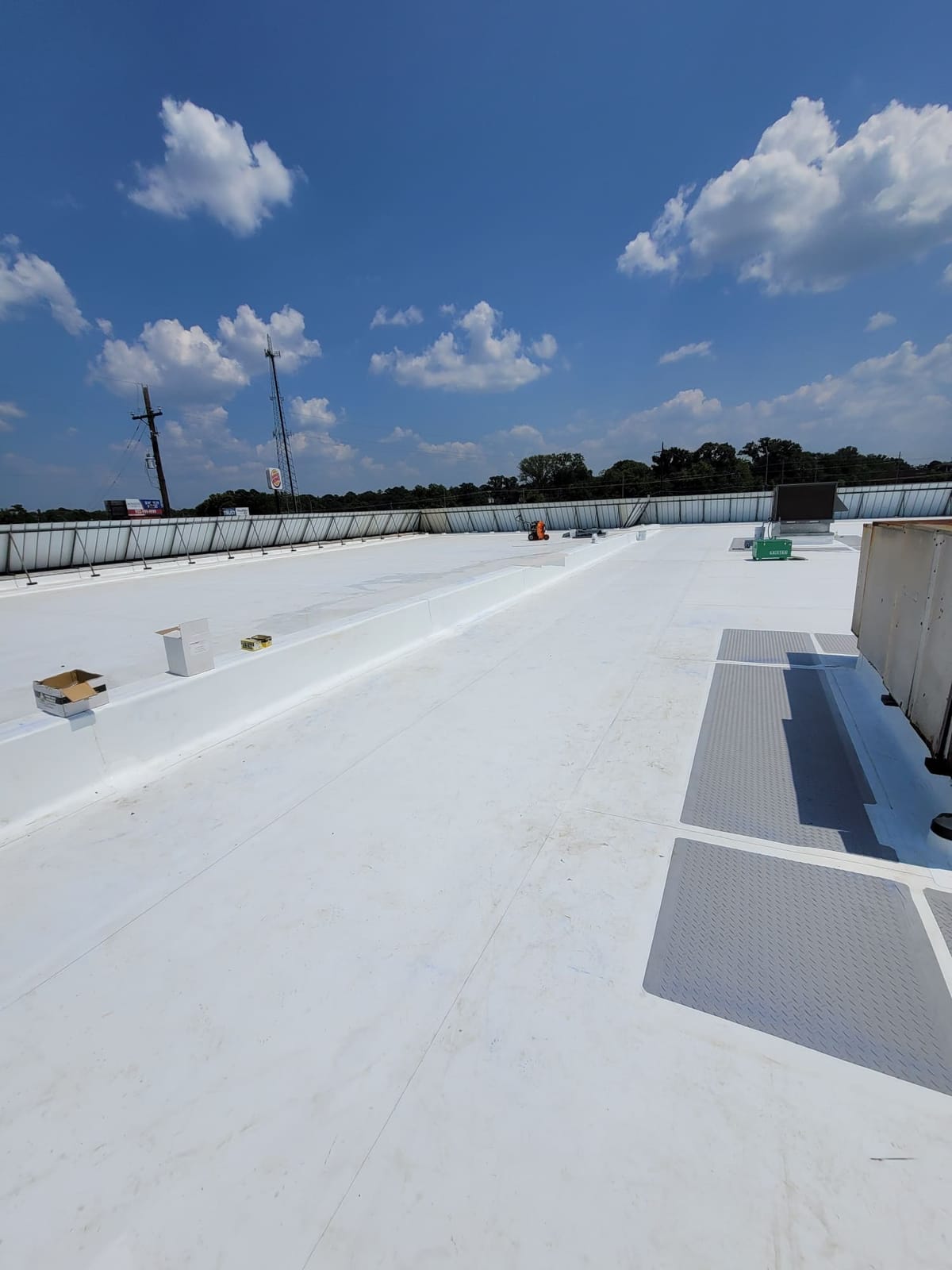 Expansive White Rooftop Under Clear Blue Sky with Scattered Clouds and Distant Utility Poles