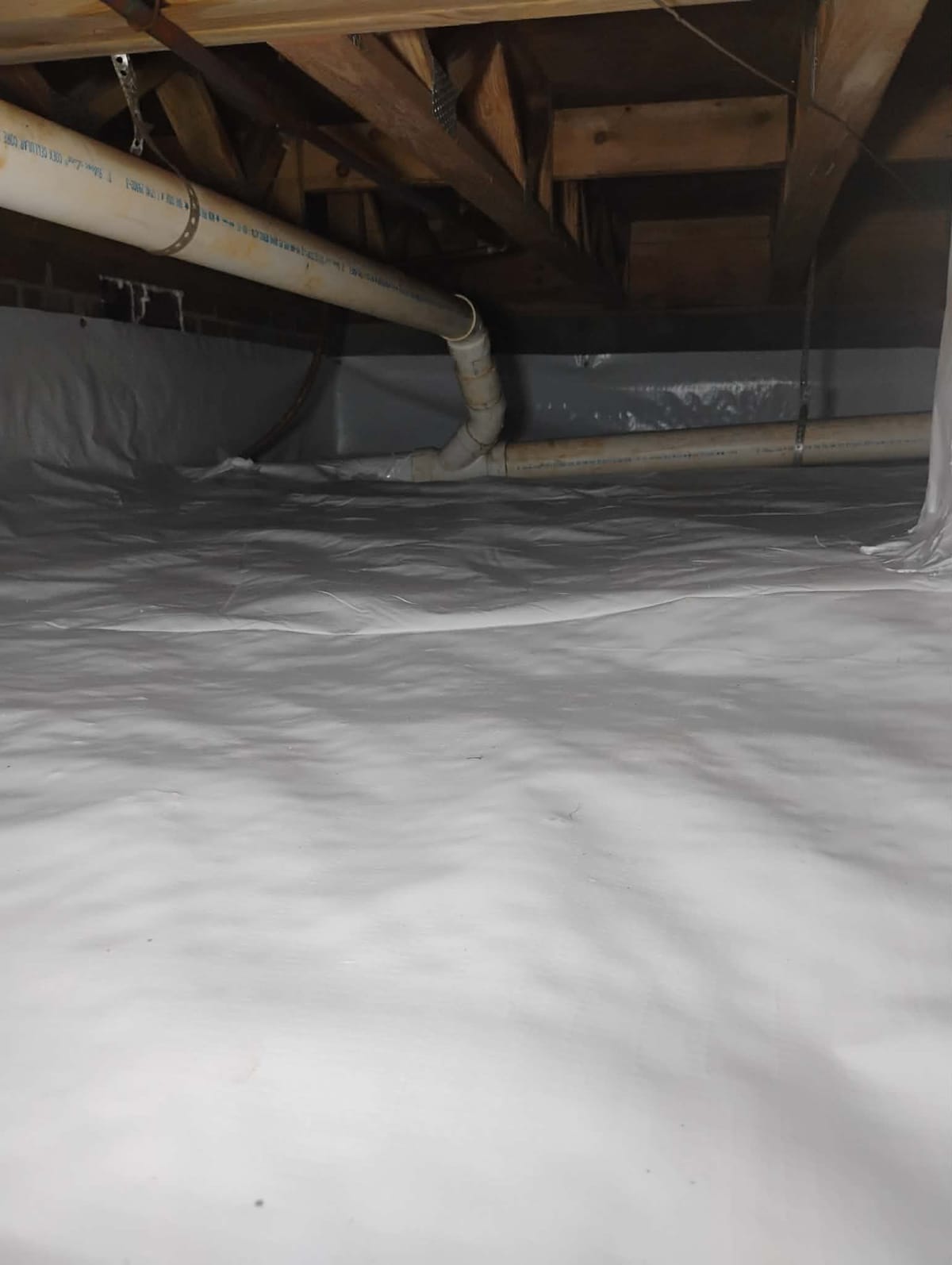 Reference photo of a lined crawl space with plumbing overhead