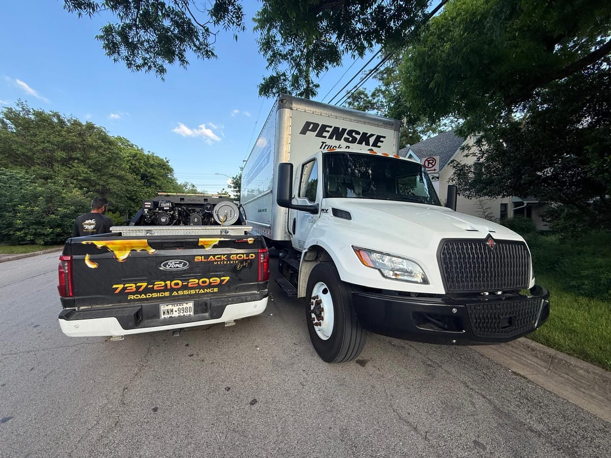 Roadside Assistance Scene with Black Pickup Truck and White Penske Rental Truck on Leafy Suburban Street
