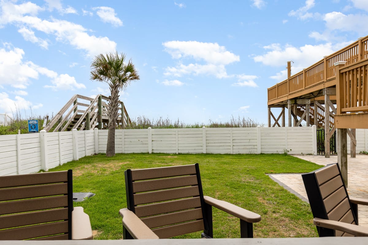 Coastal Backyard with Wooden Deck and White Fence Overlooking Ocean Access Pathway