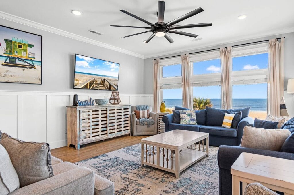 Coastal-Themed Living Room with Ocean View, Beach Artwork, and Modern Decor Featuring Blue Sofas and Large Windows