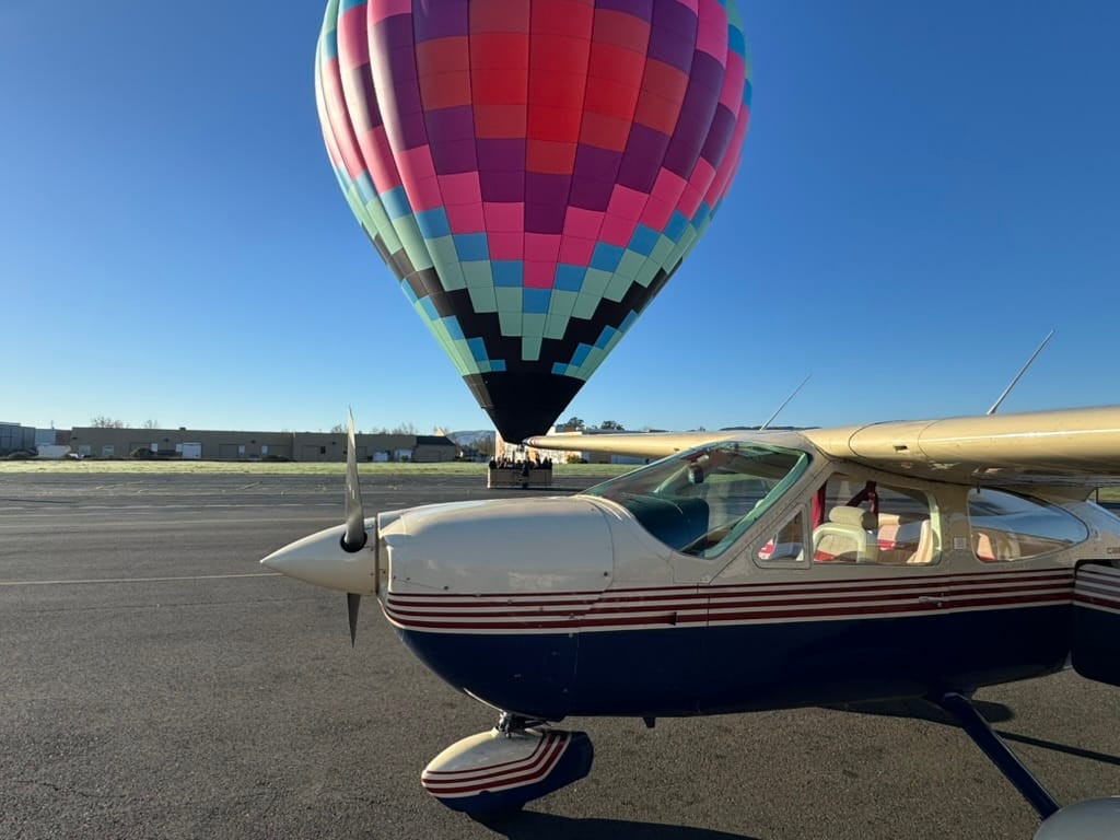 Colorful Hot Air Balloon and Vintage Airplane on Clear Day at Airport Runway