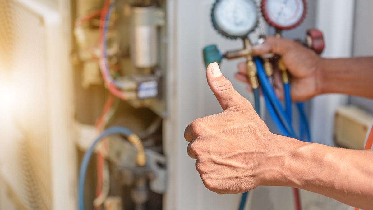 Technician Giving Thumbs Up While Using Pressure Gauges to Inspect HVAC System
