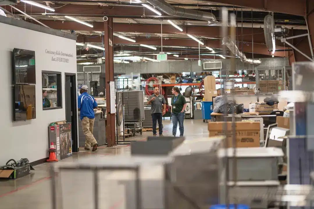 Busy Industrial Workshop with Workers Engaged in Various Tasks Amidst Machinery and Equipment Under Bright Overhead Lighting