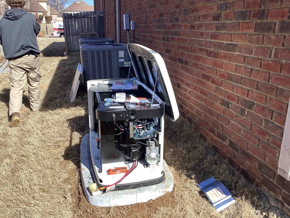 Technician Walking Away from Open Generator and HVAC Units Next to Brick Wall on Sunny Day