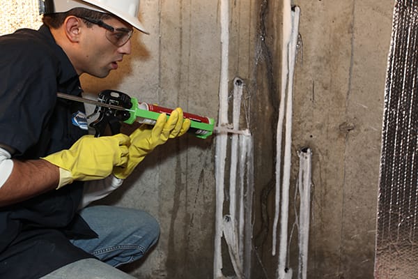 Worker in Safety Gear Applying Sealant to Cracked Concrete Wall for Structural Repair and Waterproofing