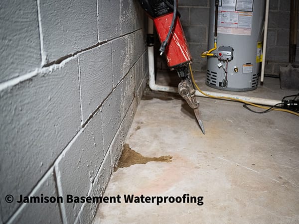 Basement Waterproofing Process with Power Tool Near Concrete Wall and Water Heater